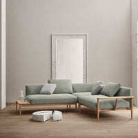 Light green sofa with a textured finish, paired with light wood accents and soft, patterned throw pillows.