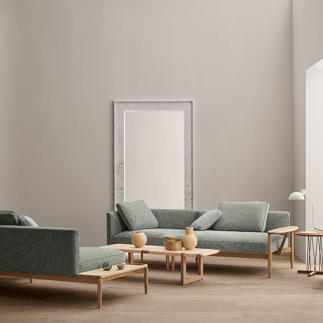 Soft green upholstery on modern sofas with light wood accents and minimalistic decor in a neutral-toned room.