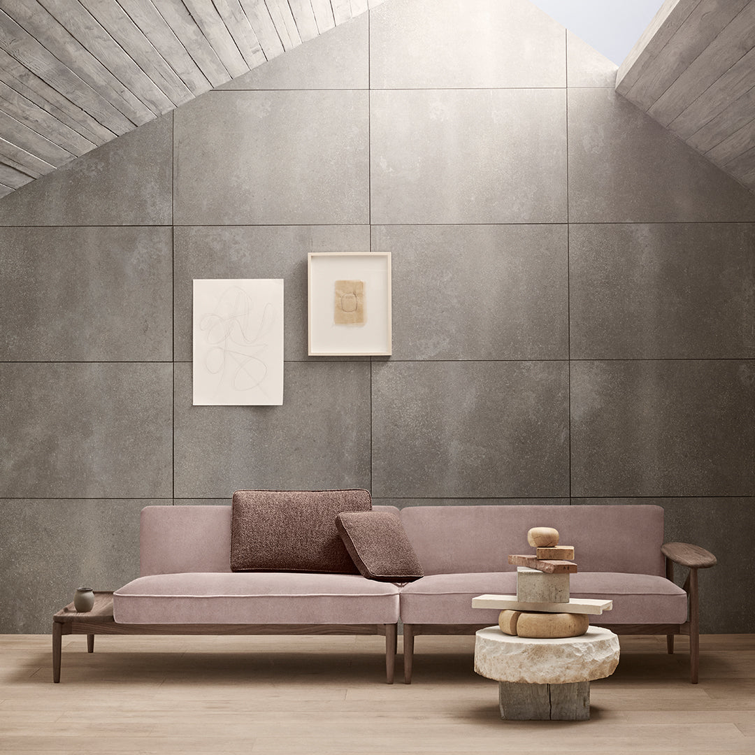 "Modern pink sofa with brown accent pillows, set against a neutral gray wall and light wooden floor."