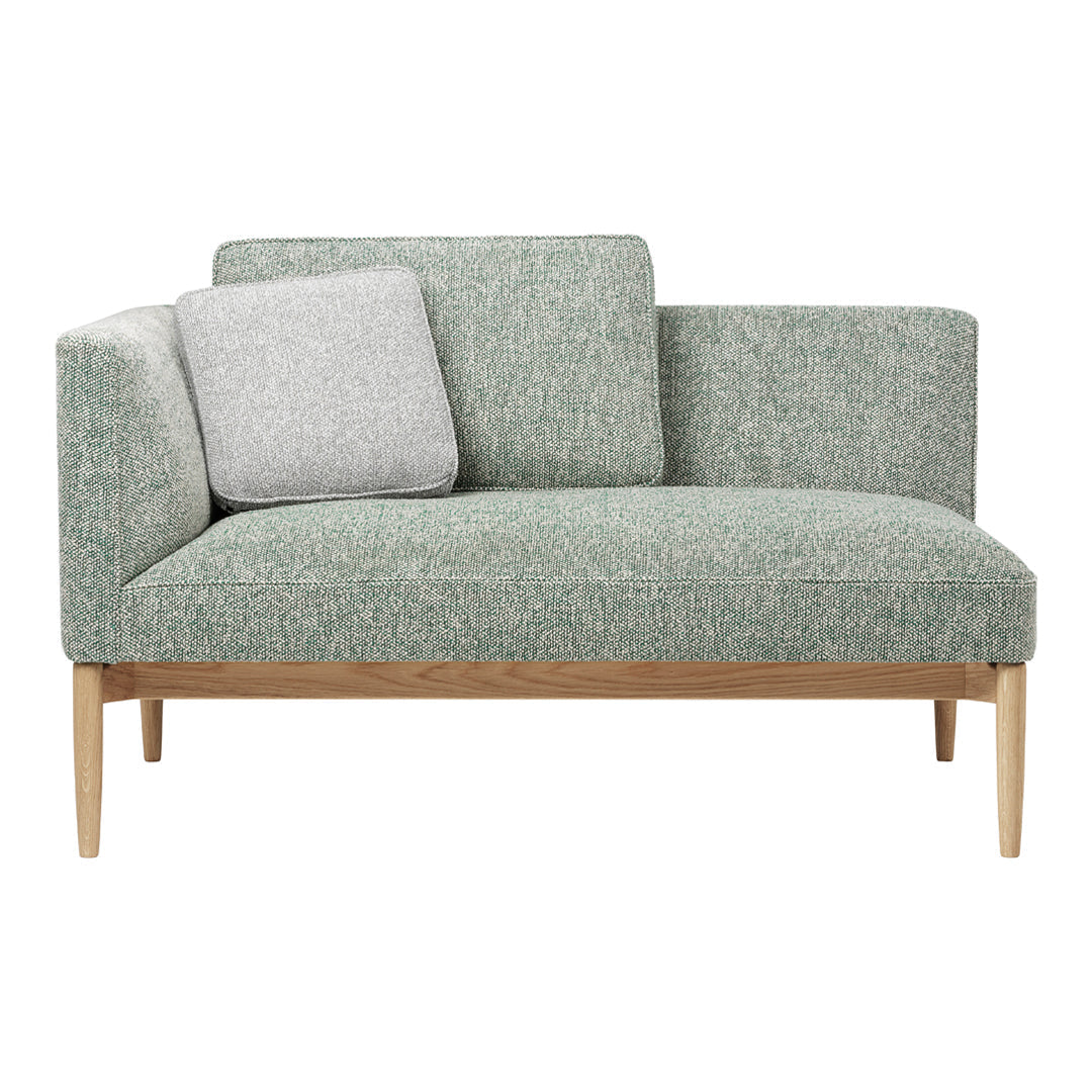 Light green upholstery with subtle texture, complemented by a grey accent pillow and natural wood legs.