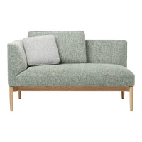 Light green upholstery with subtle texture, complemented by a grey accent pillow and natural wood legs.