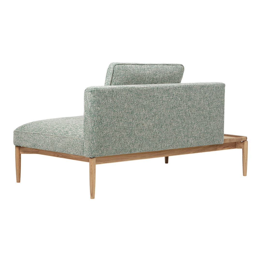 Light green textured upholstery with a subtle pattern, paired with a natural wood frame. Modern chaise lounge design.