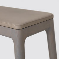 Beige leather top with smooth gray wooden legs, minimalist design. Perfect for modern decor.