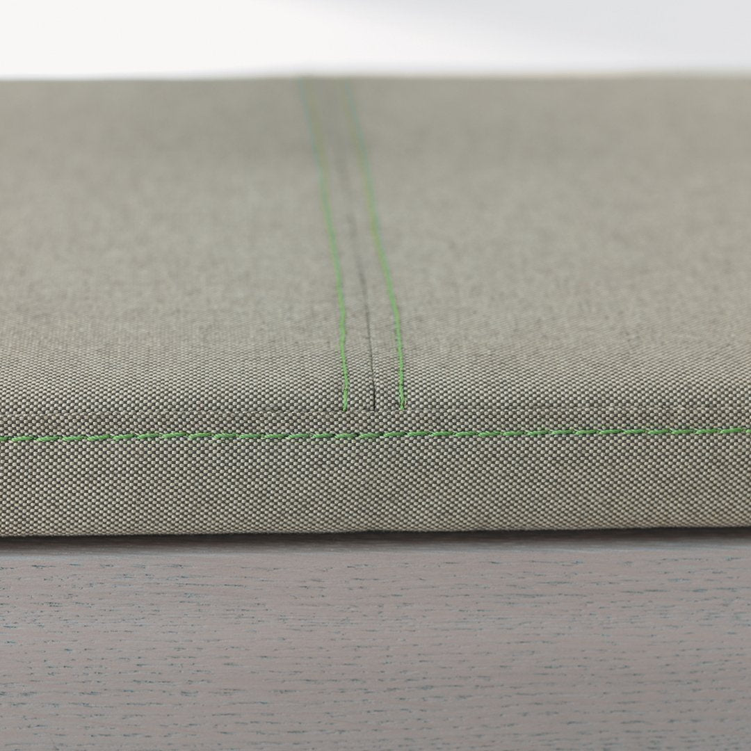 Light gray fabric with subtle texture and contrasting green stitching detail. Ideal for modern home decor.