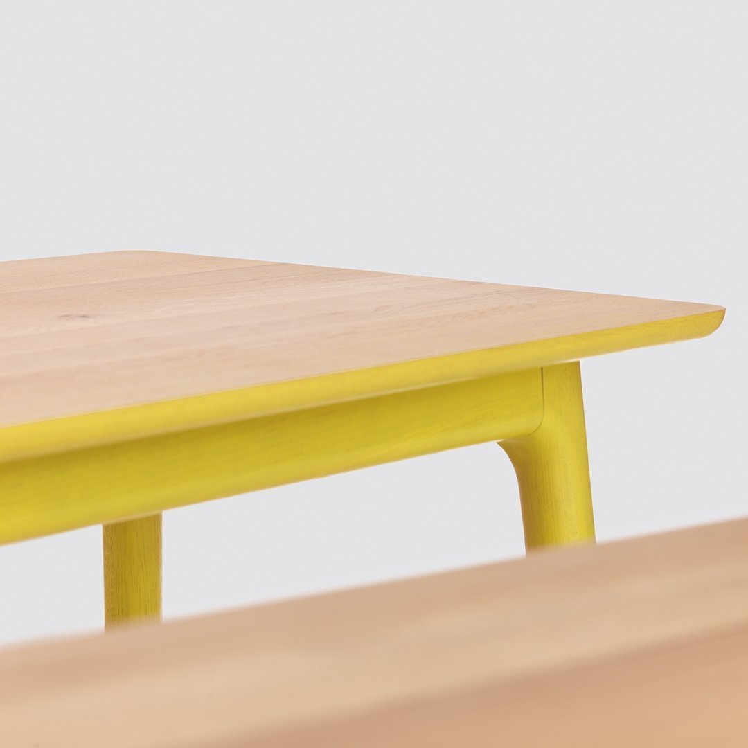 Wood table with a natural light wood top and vibrant yellow legs, showcasing a modern and stylish design.