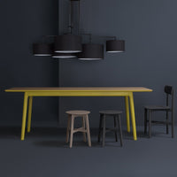 Stylish yellow table with sleek black stools and modern black lamps, set against a dark blue backdrop.