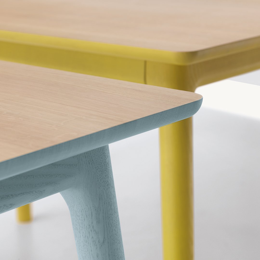Light wood tabletop with pastel blue and vibrant yellow legs, featuring sleek, minimalist design.