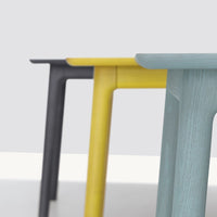 "Colorful table legs in black, yellow, and light blue with a modern design against a neutral background."