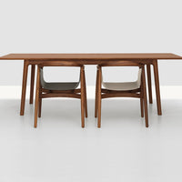Wooden dining table with warm brown finish and two modern chairs in light gray and soft beige upholstery.