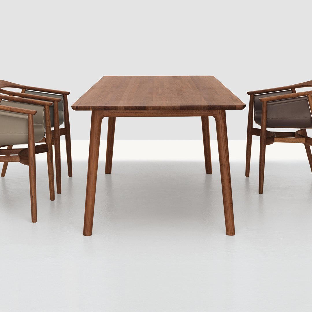 "Natural wood dining table in warm brown tones with minimalist design, complemented by beige and brown pattern chairs."