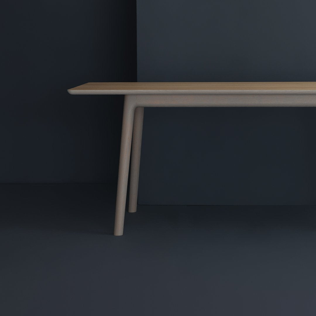 Light beige table with smooth, minimalist design set against a dark blue background. Clean lines and modern style.