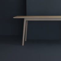 Light beige table with smooth, minimalist design set against a dark blue background. Clean lines and modern style.