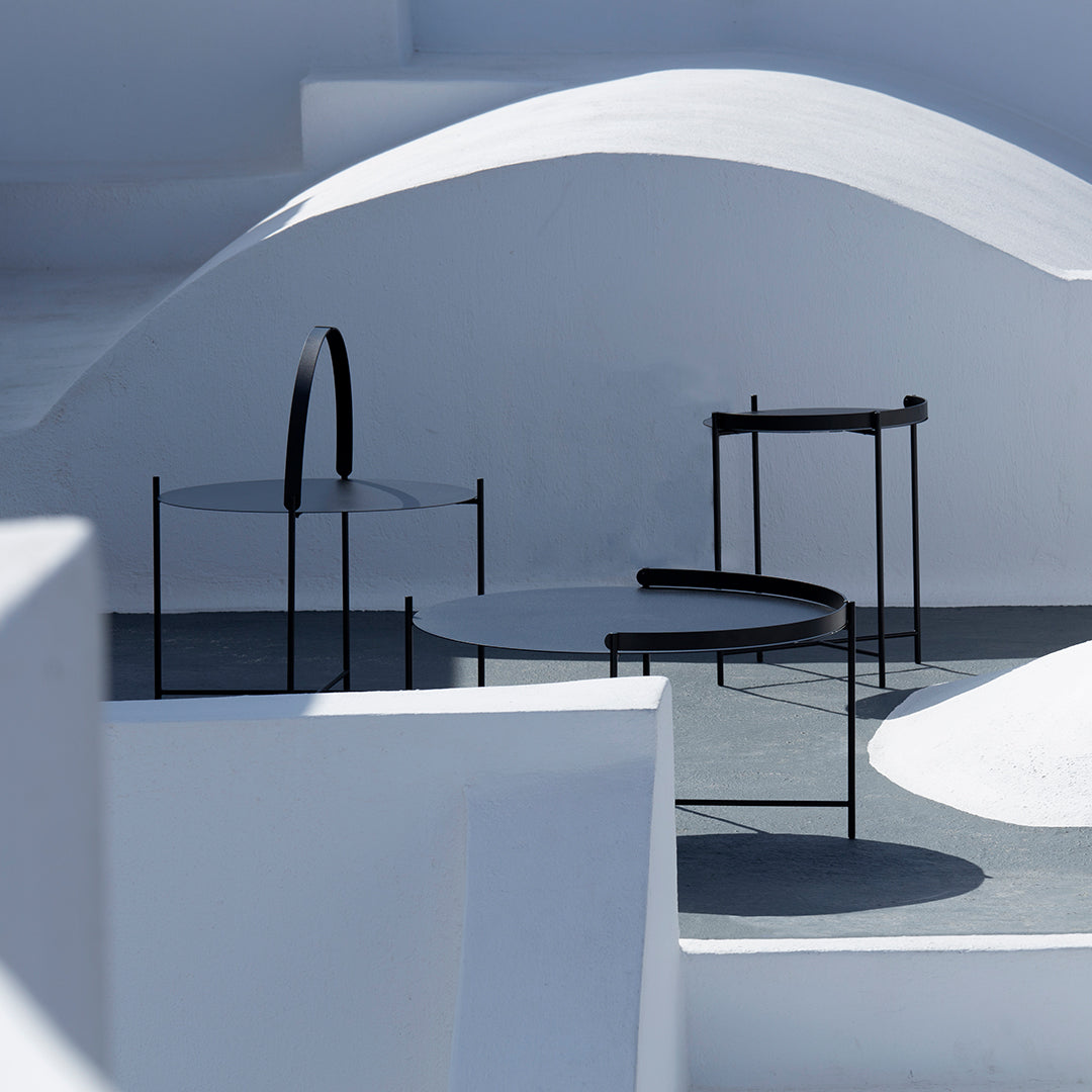 Modern black furniture against minimalist white and gray geometric architecture. Clean lines and contrasting colors.