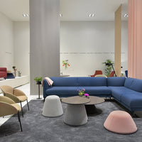 "Modern living room with a blue sofa, pastel accent chairs, gray rug, and colorful cylindrical stools."
