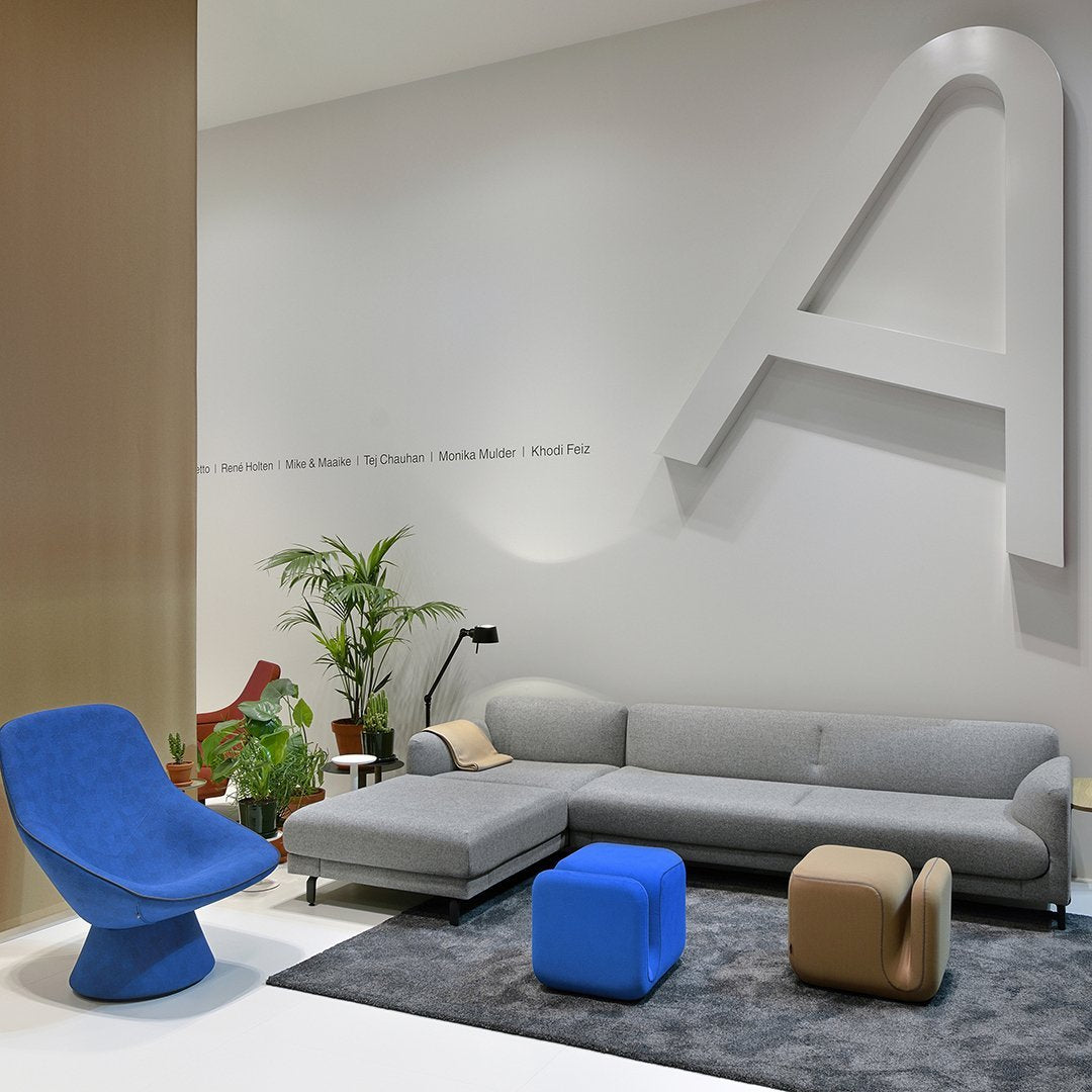 Modern living room featuring a gray sectional sofa, blue accent chair, and colorful geometric stools in a stylish setting.