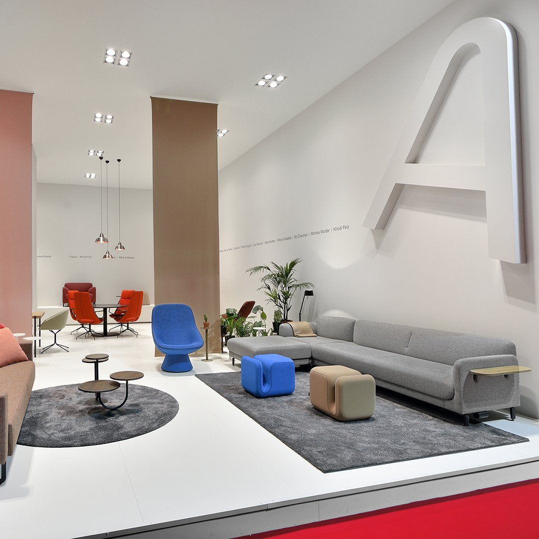 Modern living room with a mix of warm tones, bright blue and gray furniture, and geometric patterns on carpets.