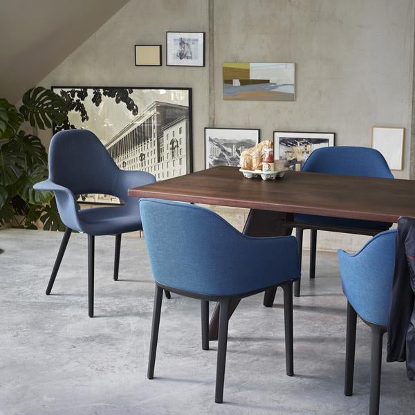 "Set of four blue upholstered chairs around a dark wood dining table in a modern, minimalist setting."