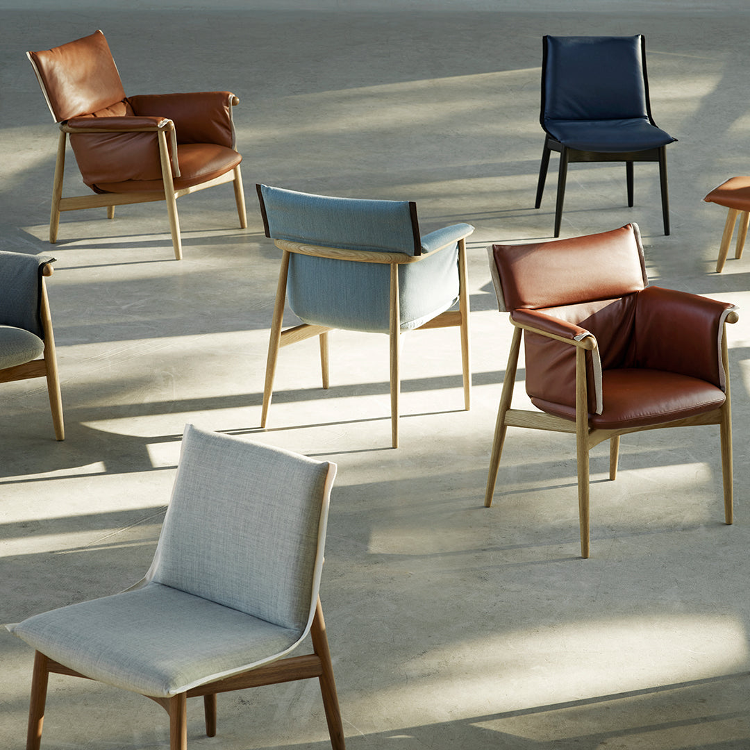 Assorted chairs in brown, blue, and light gray, featuring a mix of leather and fabric textures against a minimalist background.