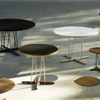 Modern round tables in black, white, and wood finishes with sleek, minimalist designs and geometric bases.