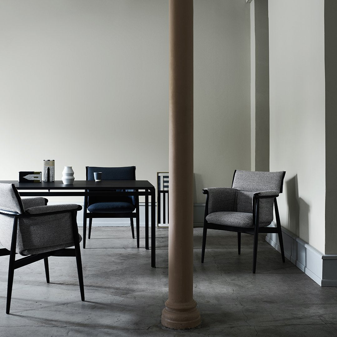 Modern chairs in muted gray and deep navy, set against a neutral-toned wall and minimalist gray flooring.