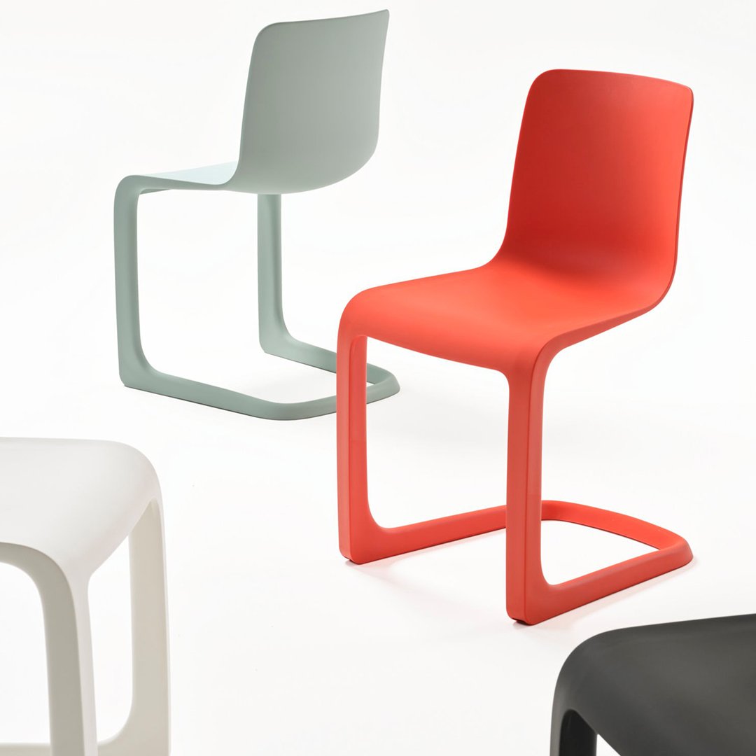 Colorful chairs in red, grey, white, and black with smooth, modern designs and playful silhouettes.
