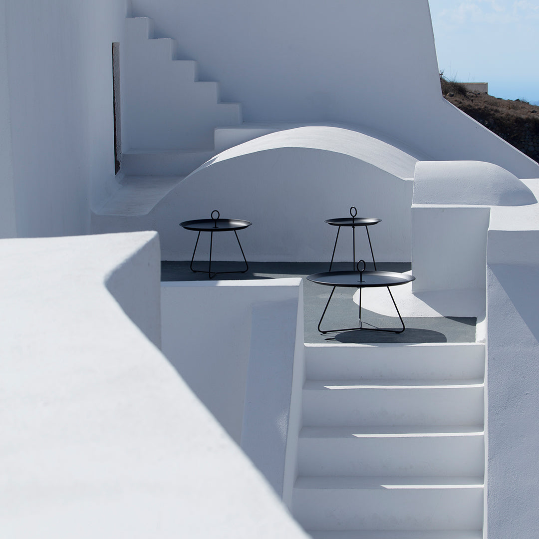 Modern outdoor setting featuring white walls, sleek black tables, and gentle geometric patterns.