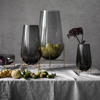 Set of three elegant glass vases with smoky gray tones and sleek gold stands, featuring a minimalist design.