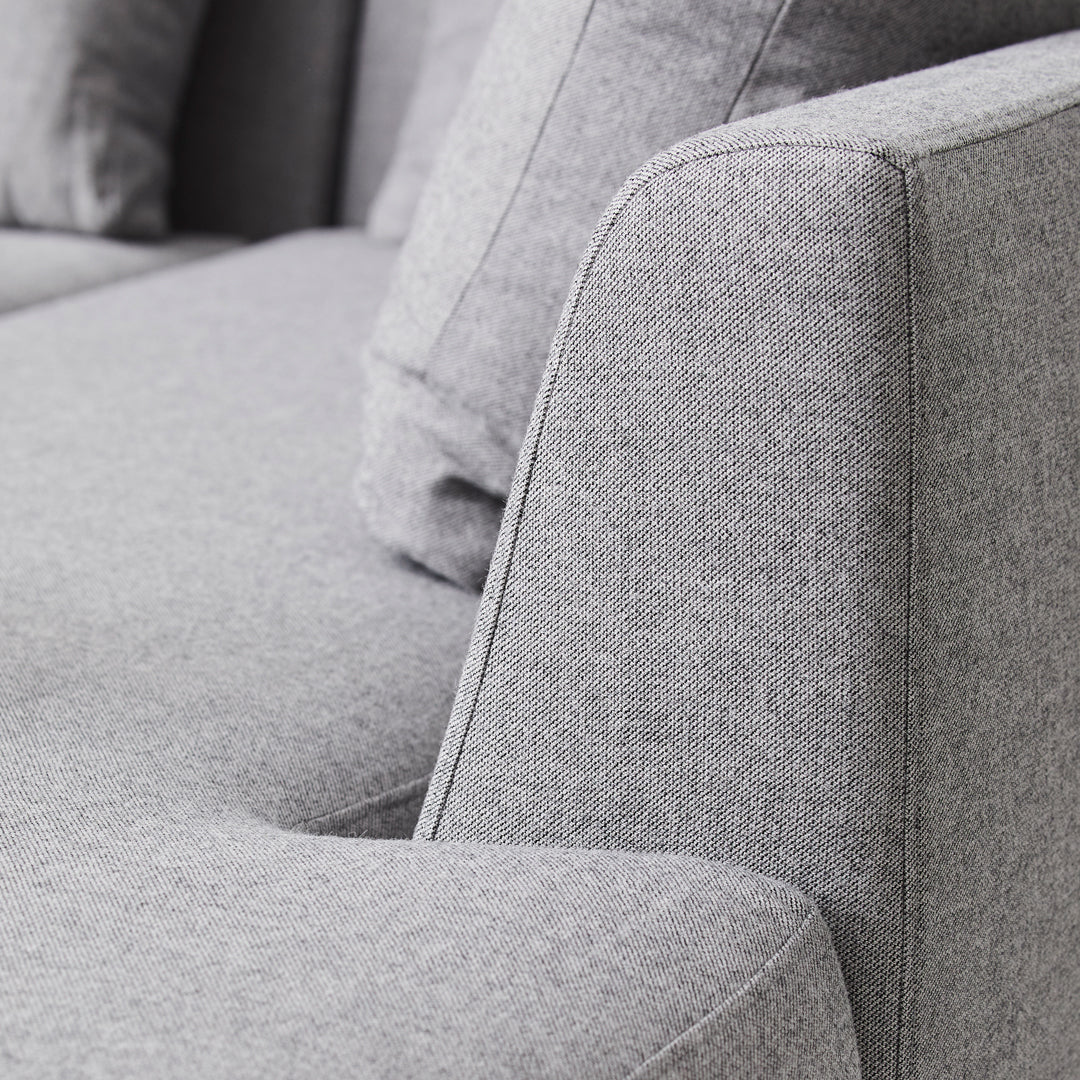 Gray fabric sofa with a smooth texture and minimalist design, showcasing subtle patterns and contemporary style.
