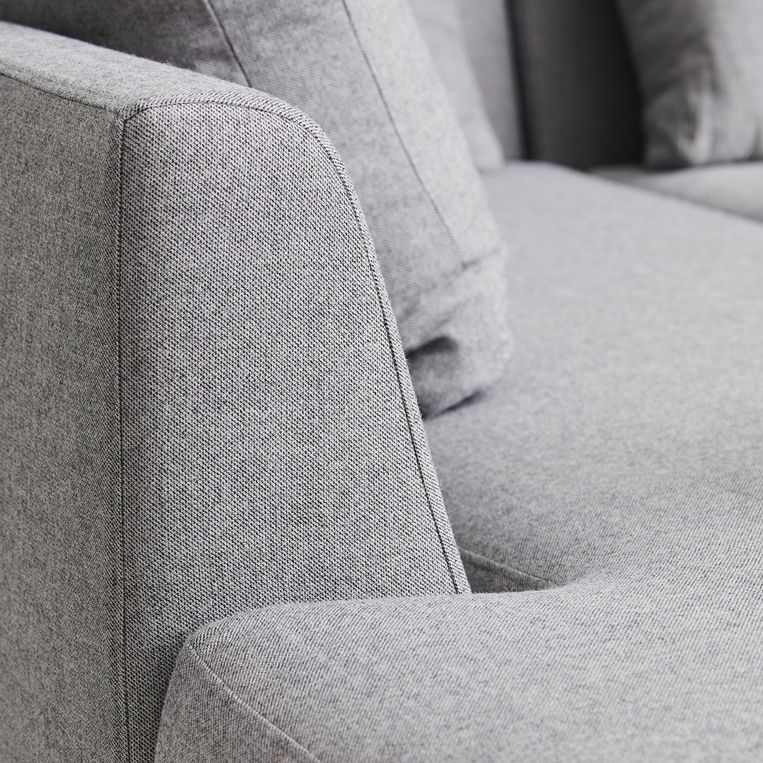 Gray upholstered sofa detail featuring a textured fabric and smooth contours. Elegant and modern design elements.