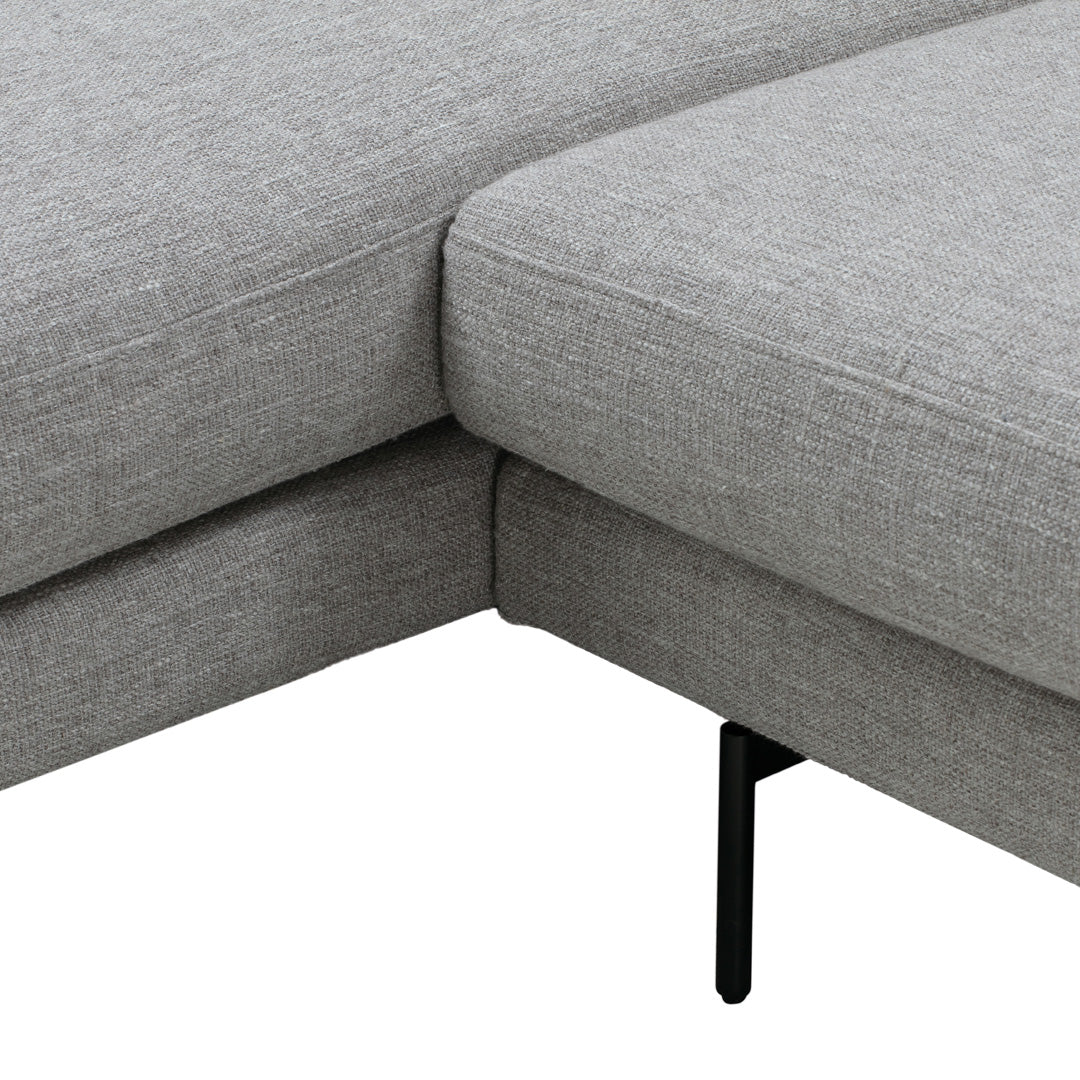 Gray sectional sofa with a textured fabric and sleek black metal legs, showcasing modern minimalist design.