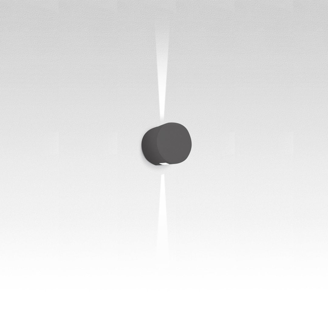 Black round wall light against a soft white background, featuring a modern minimalist design.