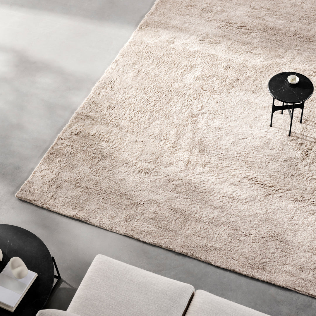 Soft beige shag rug with subtle texture, complementing modern decor in a neutral-toned living space.