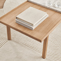 Natural wood finish coffee table with minimalist design, featuring soft beige and cream tones in the surrounding decor.