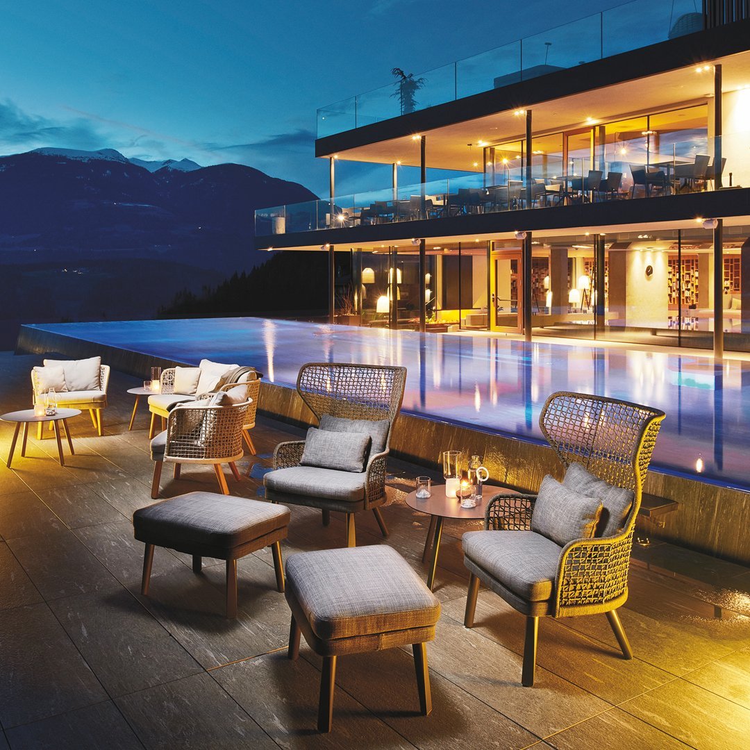 Elegant outdoor seating in gray and beige, featuring woven patterns, set against a serene evening poolside backdrop.