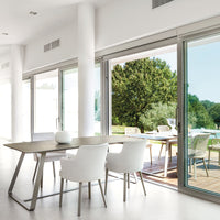 Modern dining room with white chairs and a light gray table, featuring soft lines and a minimalist design.