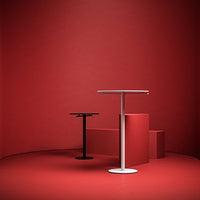 "Modern black and white tables against a bold red backdrop, showcasing sleek lines and minimalist design."
