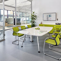 Modern conference room featuring a sleek white table and vibrant green chairs, complemented by a neutral gray floor.