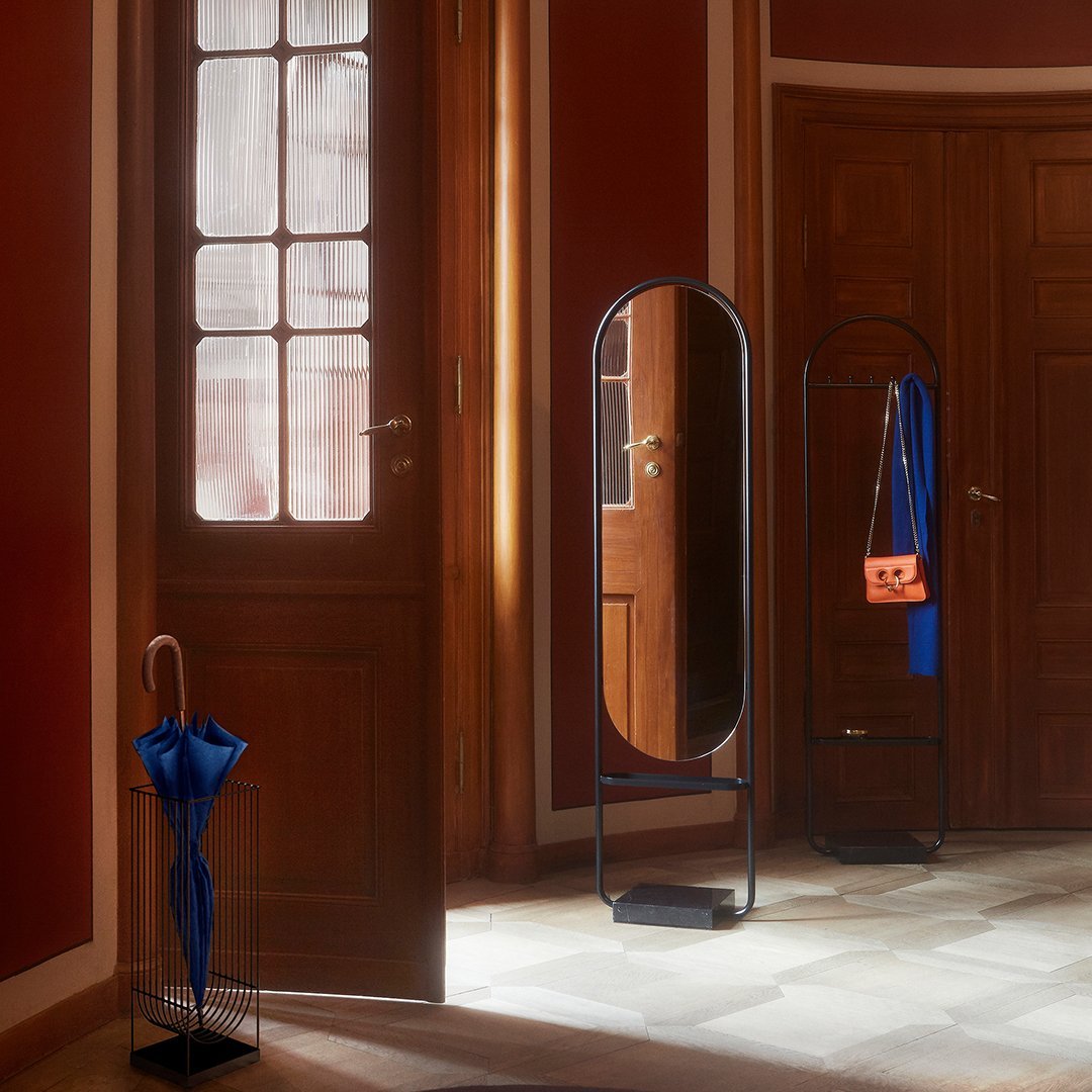 "Modern room with a blue umbrella and stylish mirror, featuring warm wood tones and a vibrant red wall."