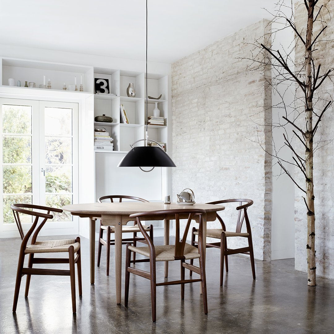 Modern wooden dining table with natural tones, complemented by black accents and a light, neutral backdrop.