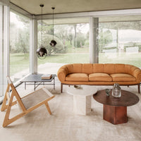 Soft orange velvet sofa, natural wood accents, minimalist design, round brown and white tables, neutral-toned rug.