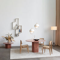 Modern dining room setup with a round pink table, light wood chairs, and soft beige curtains against a neutral backdrop.