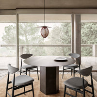 "Modern round table in charcoal grey with light grey chairs, soft beige rug, and a copper pendant light."