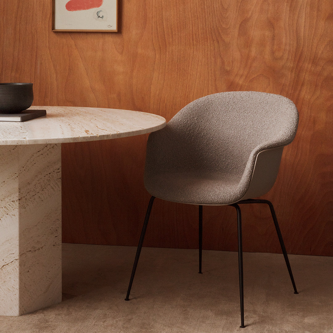Gray upholstered chair with black metal legs, set against a warm wood backdrop and a marble table.