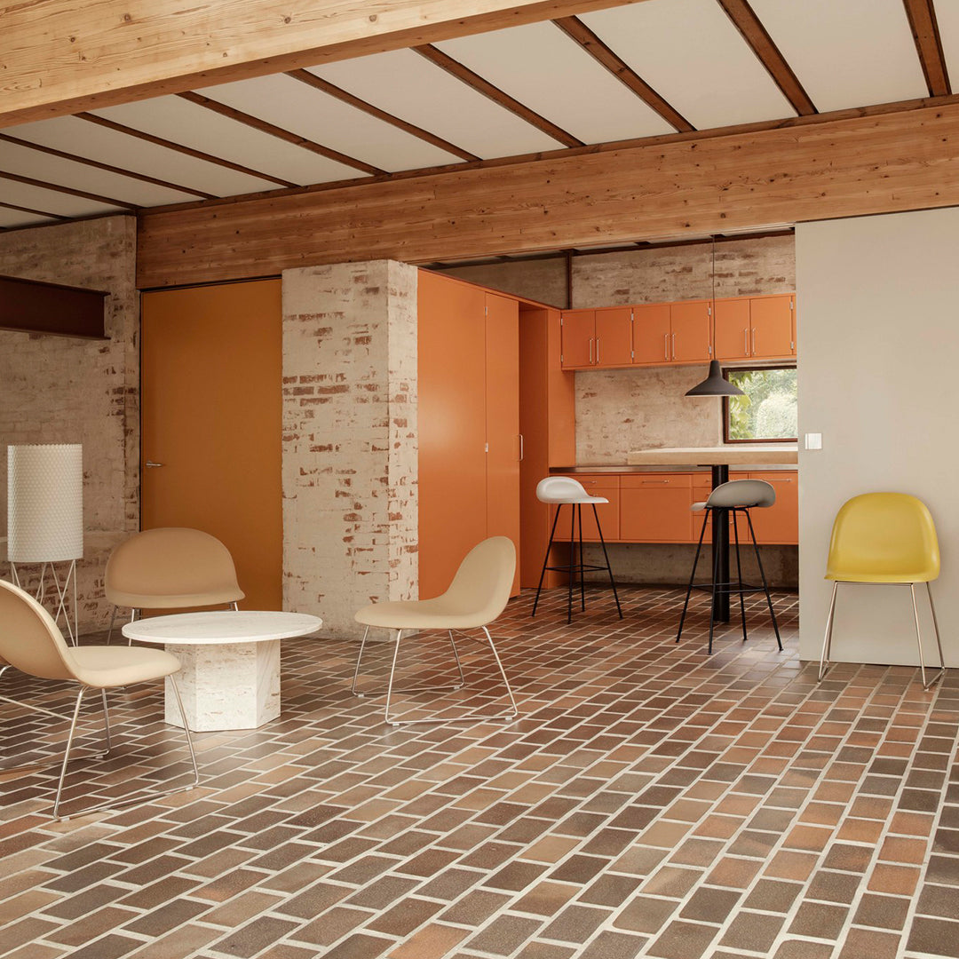 Modern interior featuring orange cabinets, beige furniture, and a patterned brown tile floor with light and dark hues.