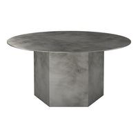 Round gray metal dining table with a smooth, brushed surface and geometric block base design.
