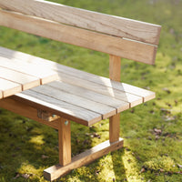 Natural wood bench with light beige planks against a green mossy background, showcasing a simple, rustic design.