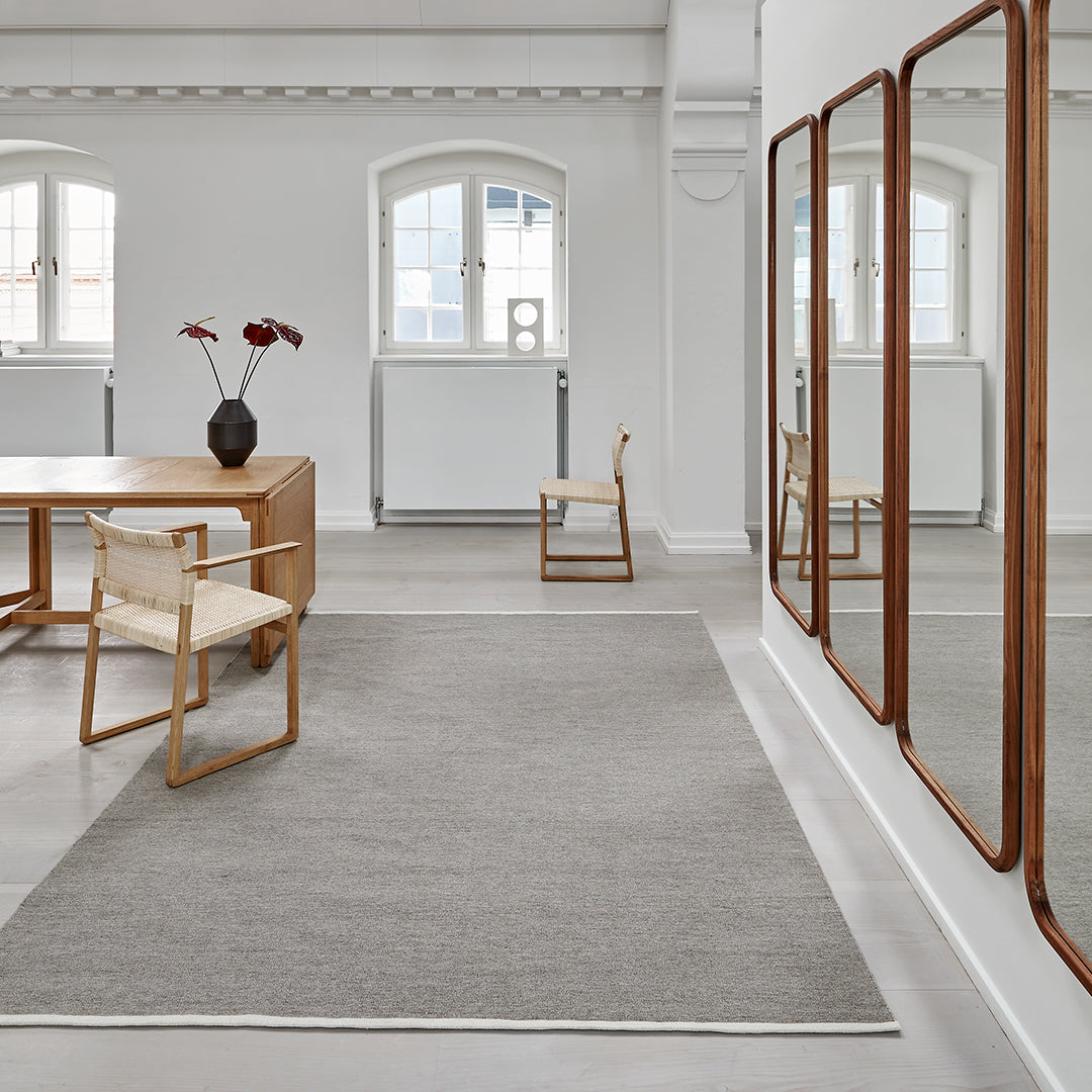 Gray area rug with a subtle texture, complemented by a minimalist white and wood interior decor.