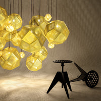 Yellow geometric pendant lights casting soft shadows, with textured patterns on a smooth beige background.