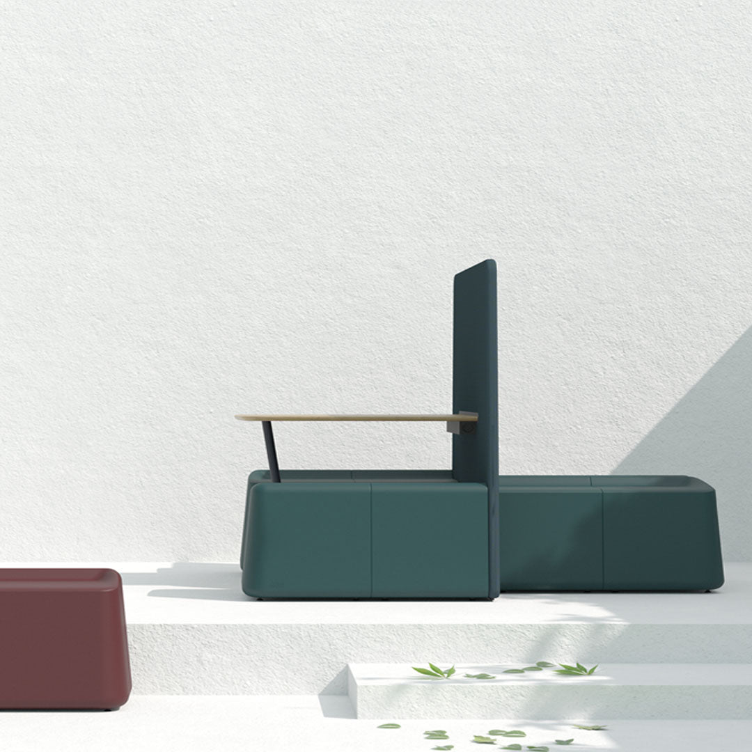 Teal armchair with a minimalist design, paired with a burgundy seating piece, set against a light textured background.