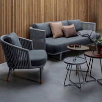 Gray fabric sofa set with soft brown cushions and sleek metal tables, set against a warm wooden backdrop.